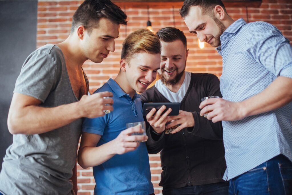 Cheerful old friends communicate with each other and phone watch, glasses of whiskey in pub